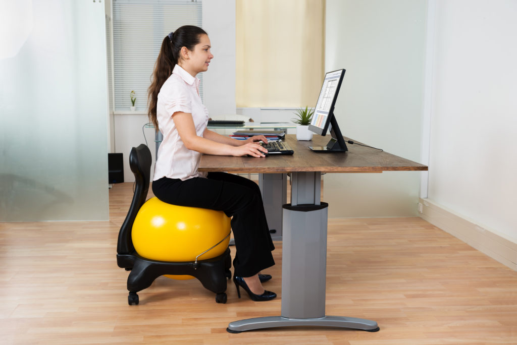 Woman on fitness ball working at desk